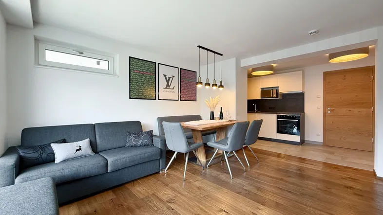 Moderner offener Wohn-Essbereich mit Holzboden, bequemer Couch und integrierter Küche.