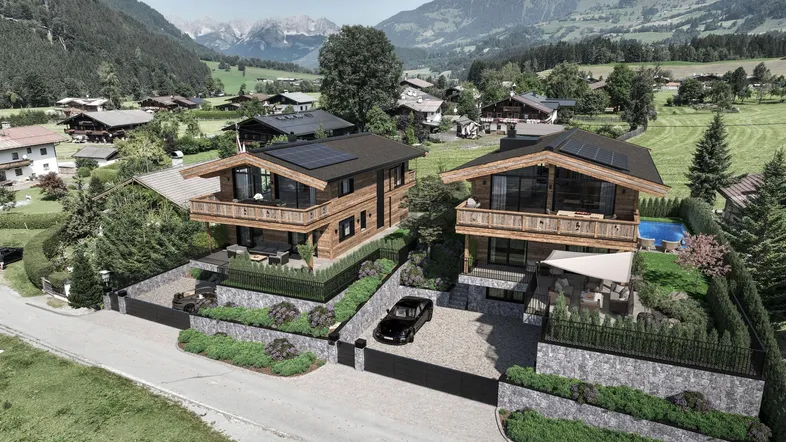 Luftaufnahme von zwei modernen Chalets in den Bergen mit Solaranlagen und Pool.