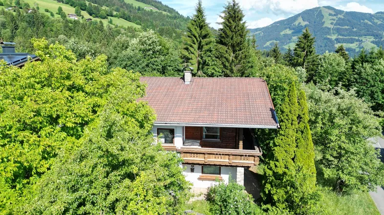 Charmantes Haus in alpiner Umgebung mit Bergblick, umgeben von üppiger Natur und Bäumen.