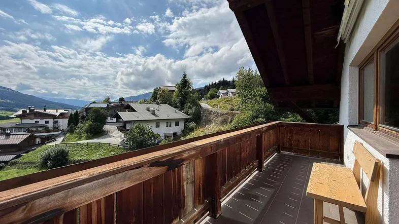 Gemütlicher Balkon mit Holzbalkon und Fliesenboden, bietet einen weiten Blick auf die umliegende Berglandschaft.
