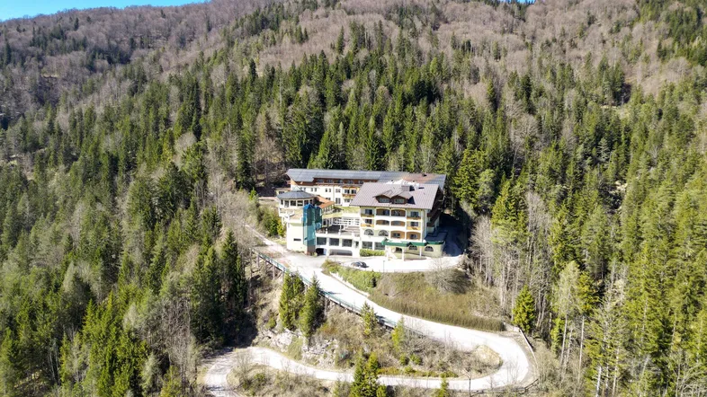 Luftaufnahme des Anwesens, eingebettet in eine bewaldete Berglandschaft mit kurviger Zufahrtsstraße.