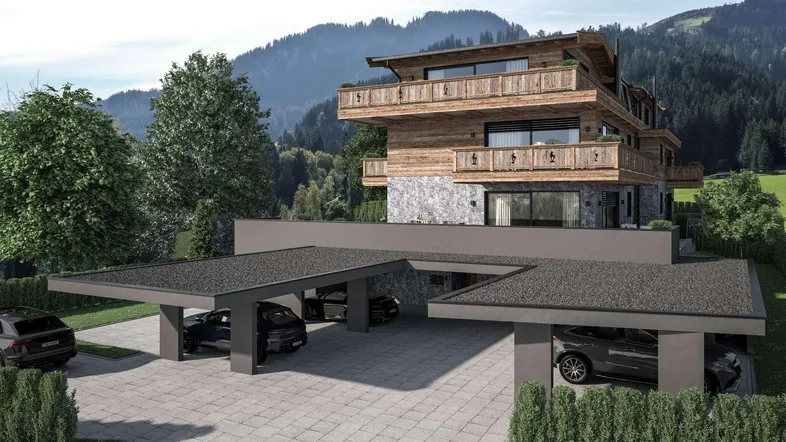 Moderne Alpenvilla mit Holzfassade, Steinelementen und überdachten Parkplätzen vor einer Bergkulisse.