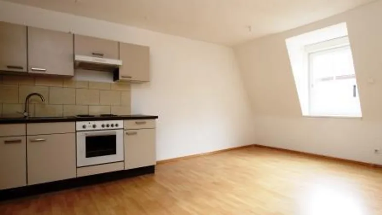 Kleine Küchenzeile in einem hellen Raum mit Dachschräge und Holzfußboden.