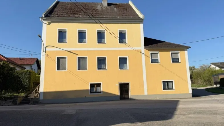 Gelbe Fassade eines traditionellen Gebäudes unter blauem Himmel.