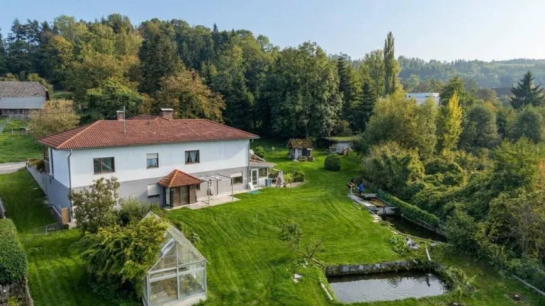Weitläufiges Anwesen mit großem Garten, Teich, Gewächshaus und umgeben von viel Grün.