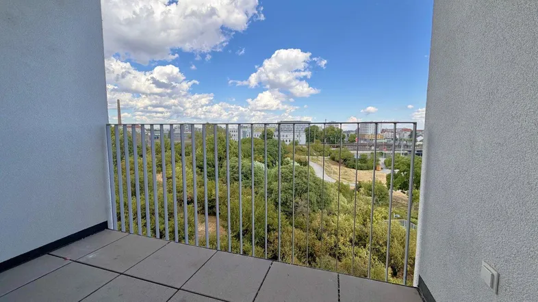 Geräumiger Balkon mit Fliesenboden und weitem Blick ins Grüne sowie auf die Stadt.