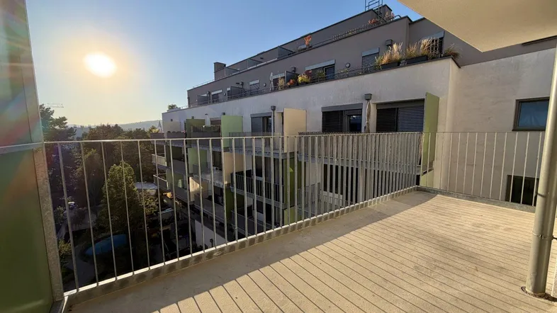 Sonnige Loggia mit Metallgeländer und Blick auf die umliegende Wohngegend.