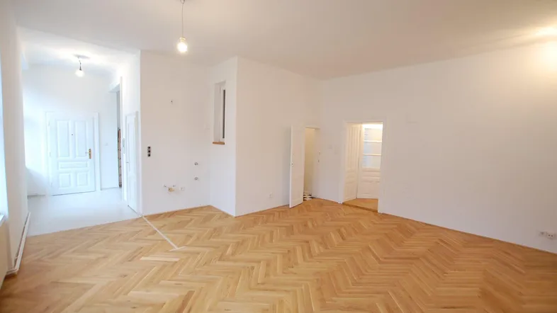 Heller Raum mit Fischgrätparkettboden und weißen Wänden, bereit zur individuellen Gestaltung.