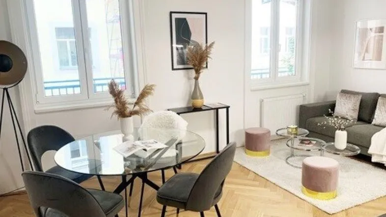 Helles Wohn- und Esszimmer mit modernem Mobiliar, Fischgrätparkett und großen Fenstern.