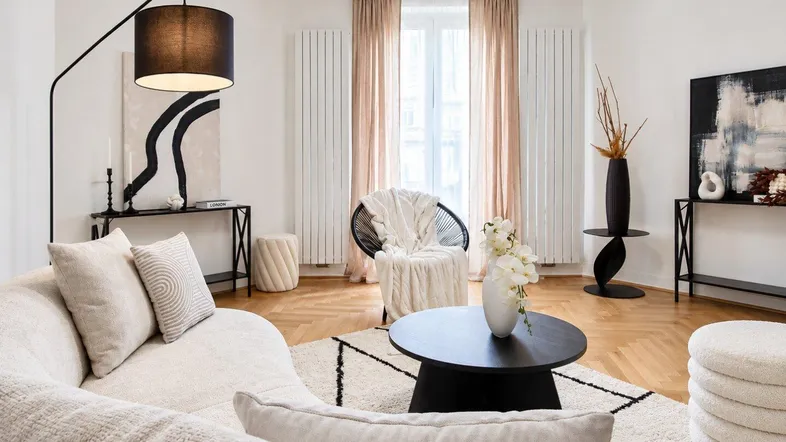 Helles Wohnzimmer mit modernem Design, beigem Sofa, schwarzem Couchtisch und Fischgrätparkett.