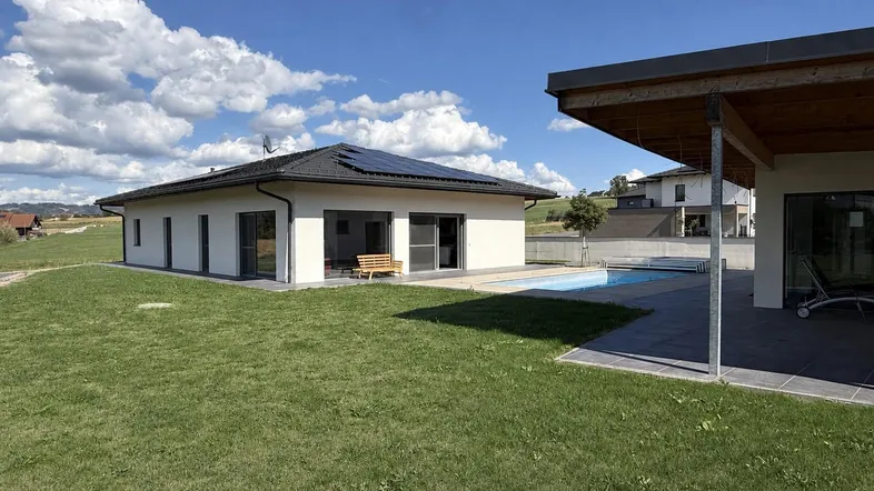 Weitläufiger Garten mit Swimmingpool und moderner Architektur des Hauses im Hintergrund.