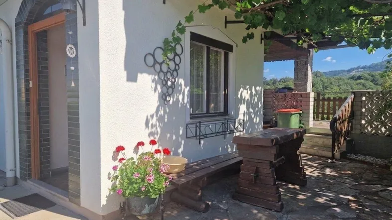 Gemütlicher Eingangsbereich mit Sitzgelegenheit, Weinreben und Blick auf die umliegende Landschaft.
