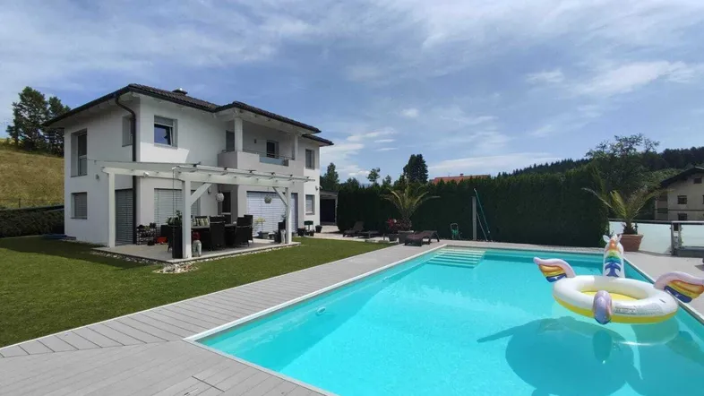 Großzügiger Gartenbereich mit Swimmingpool, Liegewiese und überdachter Terrasse.