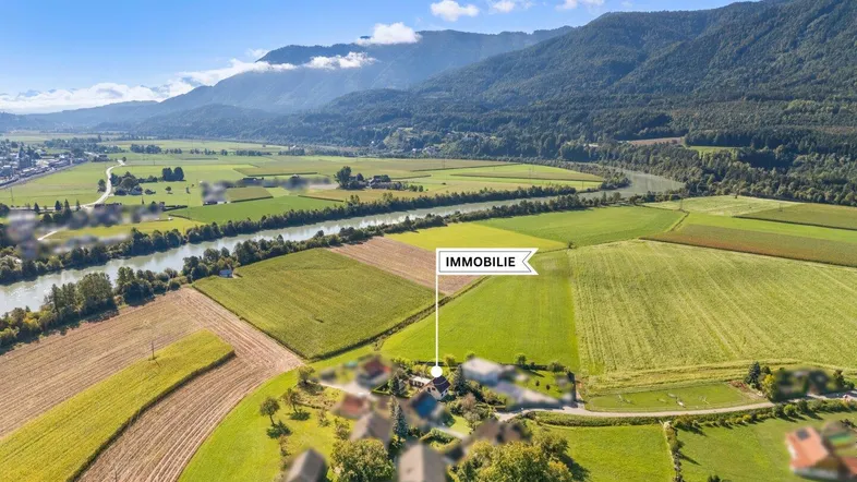 Luftaufnahme der Immobilie in ländlicher Umgebung mit Fluss und Bergen im Hintergrund.