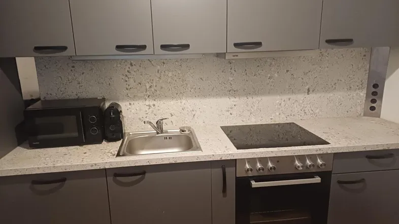 Moderne Küche mit grauen Schränken, Induktionskochfeld, Backofen und Mikrowelle, ideal für den täglichen Gebrauch.