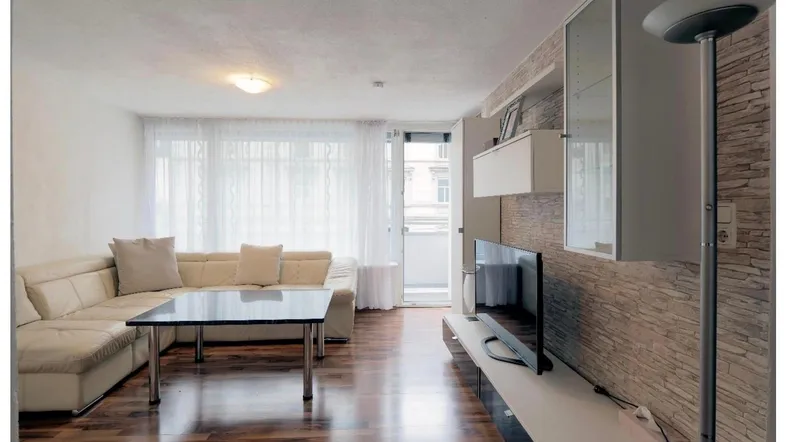 Helles Wohnzimmer mit beigem Sofa, Holzboden und einer modernen Steinwand als Akzent.