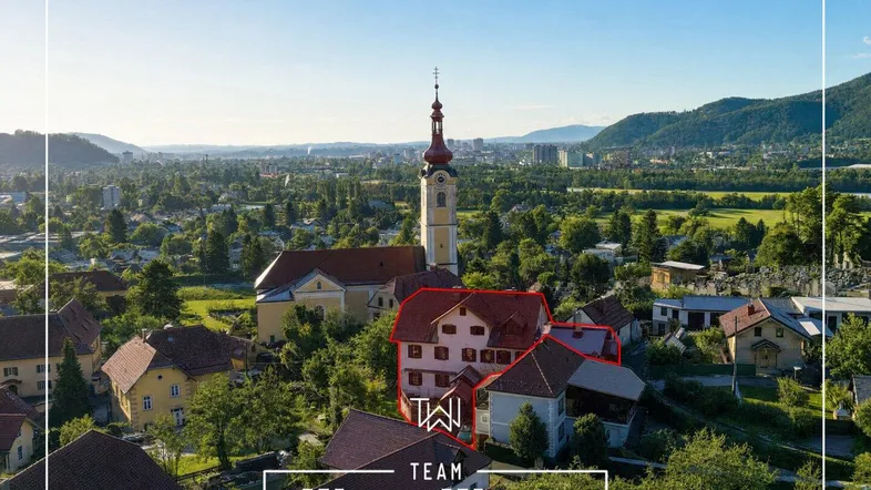 Luftaufnahme eines historischen Gebäudes mit Kirche und Bergblick in einer malerischen Stadt.
