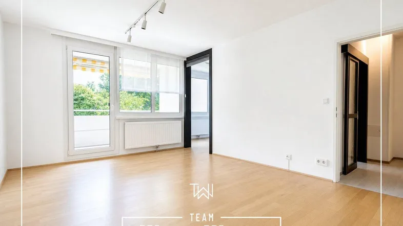 Helles Wohnzimmer mit Parkettboden, weißen Wänden und Zugang zu einem Balkon, ideal für individuelle Gestaltung.