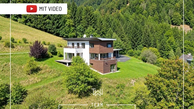 Moderne Villa in Hanglage, umgeben von grünen Wäldern und Natur mit mehreren Balkonen und Terrassen.