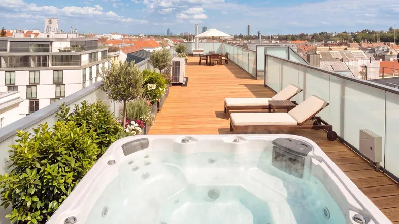 Große Dachterrasse mit Whirlpool, Liegestühlen und Panoramablick über die Stadt.
