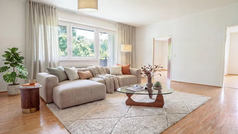 Helles Wohnzimmer mit beigem Sofa, Holzboden und Blick ins Grüne, ideal zum Entspannen.