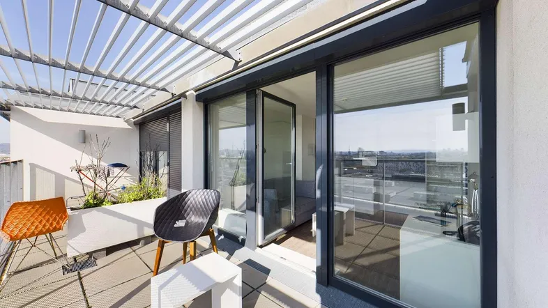 Geräumige Dachterrasse mit Pergola, modernen Sitzgelegenheiten und weitem Blick über die Stadt.