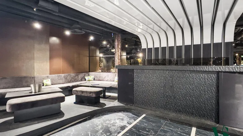 Elegante Lounge mit dunklem Fliesenboden, bequemen Sitzgelegenheiten und einer markanten Deckenverkleidung.