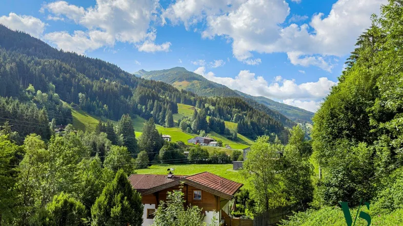Idyllisches Haus in den Bergen mit weitem Blick über das grüne Tal und die umliegende Natur.