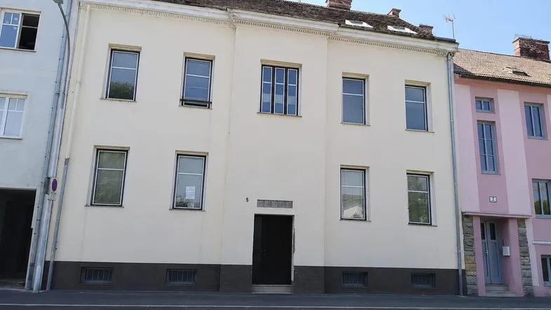 Klassisches Mehrfamilienhaus mit heller Fassade und mehreren Fenstern an einer Straße gelegen.