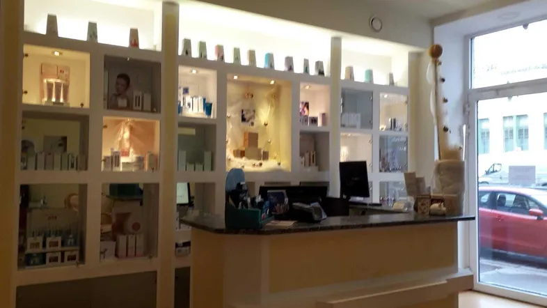 Empfangsbereich mit Theke und beleuchteten Regalen, die Produkte präsentieren, und einem Blick nach draußen.