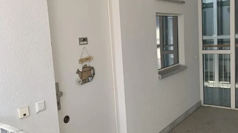Heller Eingangsbereich mit weißer Tür, kleinen Fenstern und Fliesenboden, einladend gestaltet.