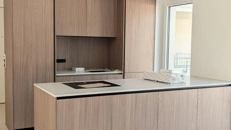 Moderne Küche mit Holzfronten, Kochinsel und Induktionskochfeld, ausgestattet mit neuen Geräten.