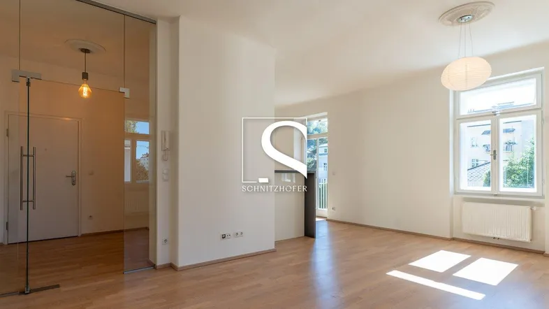 Helles Wohnzimmer mit Parkettboden, weißen Wänden und einer modernen Glastür.