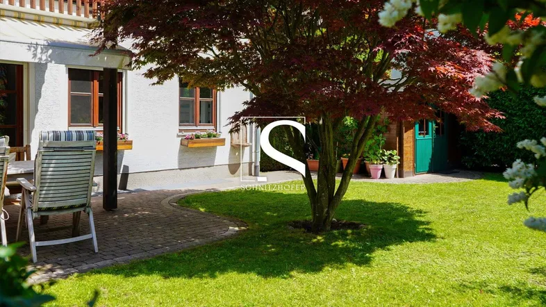 Gemütliche Terrasse mit Gartenmöbeln, umgeben von Grün und einem schönen Ahornbaum.