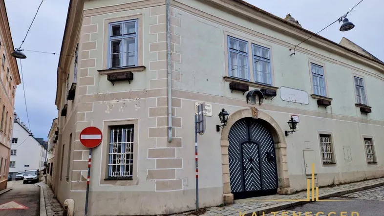 Historisches Eckgebäude mit gepflasterter Straße und traditioneller Architektur in einer Gasse.