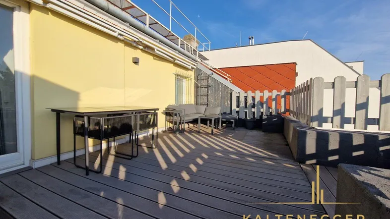 Weitläufige Dachterrasse mit Holzbelag und verschiedenen Sitzbereichen unter blauem Himmel.
