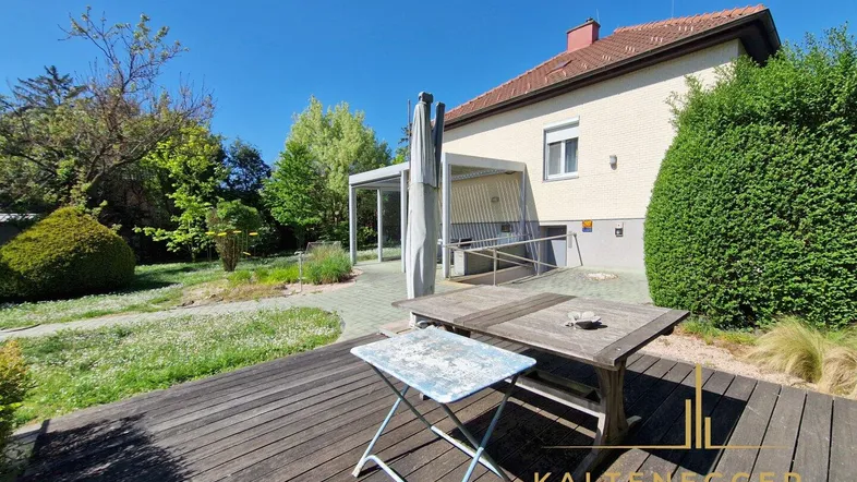 Holzterrasse mit Gartenmöbeln und Blick auf den gepflegten Gartenbereich des Hauses.