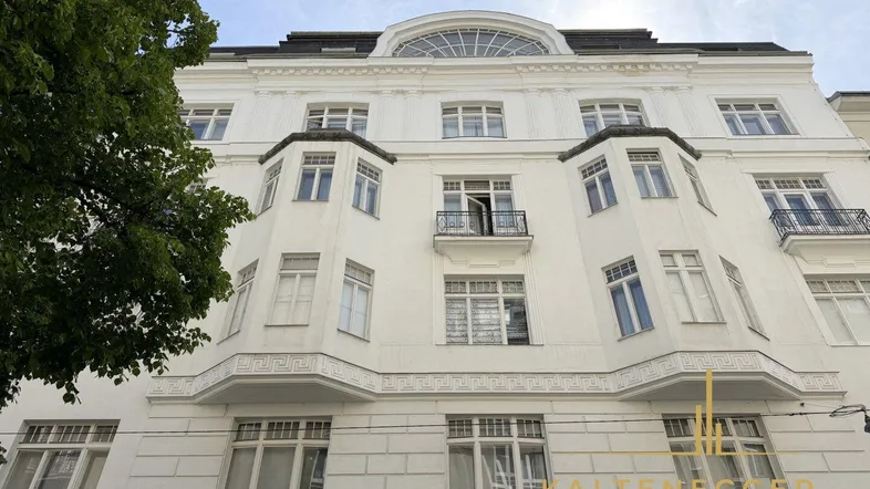 Elegante weiße Fassade eines Altbaus mit klassischen architektonischen Details und Balkonen.