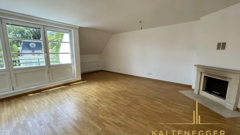 Helles Wohnzimmer mit Parkettboden, Kamin und großen Fenstern mit Blick ins Grüne.