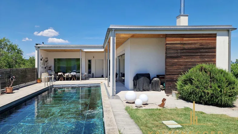 Außenansicht des modernen Hauses mit Poolbereich und gepflegtem Rasen an einem sonnigen Tag.