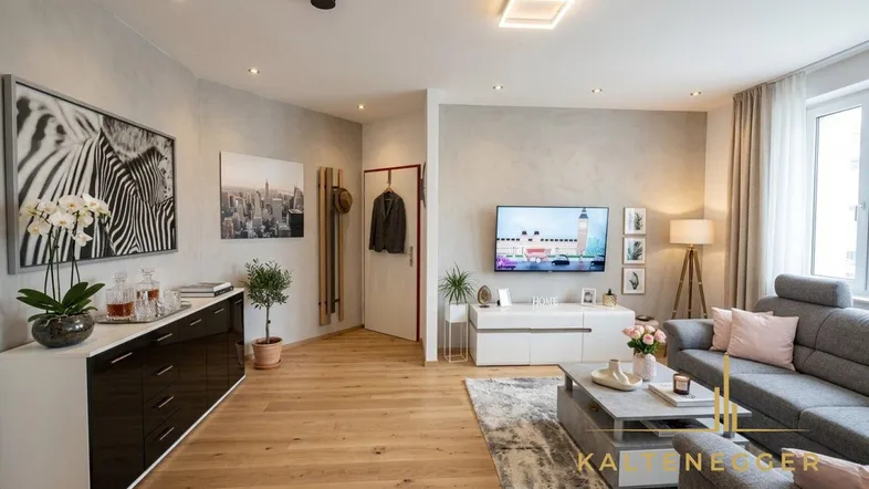 Helles Wohnzimmer mit modernem Design, Holzboden und bequemer grauer Couch.