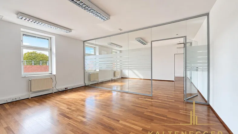Geräumiges Büro mit Holzboden und modernen Glaswänden, die separate Arbeitsbereiche schaffen.