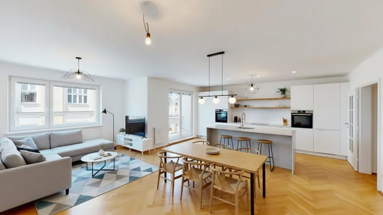 Moderner offener Wohn-Essbereich mit integrierter Küche, Parkettboden und Zugang zum Balkon.