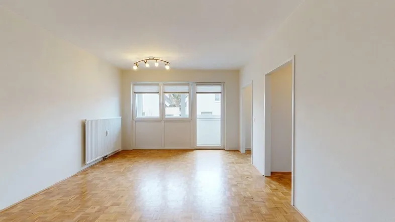 Helles Wohnzimmer mit Parkettboden, großen Fenstern und Zugang zum Balkon, modern eingerichtet.