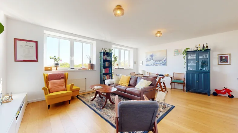 Helles, offenes Wohn- und Esszimmer mit Holzboden, bequemen Möbeln und großen Fenstern.