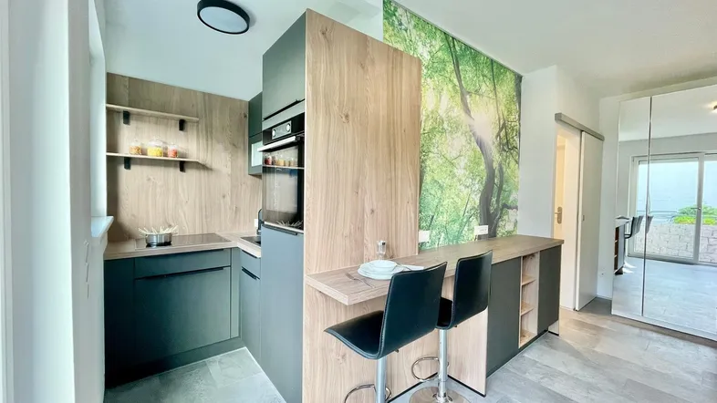 Moderne Küche mit integrierten Geräten, Frühstücksbar und einer auffälligen Natur-Wandtapete.