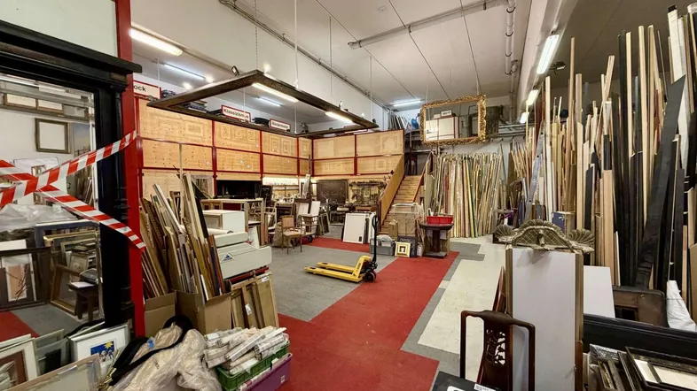 Großer, offener Werkstatt- und Lagerbereich mit hohen Decken und vielen Materialien für die Rahmenherstellung.