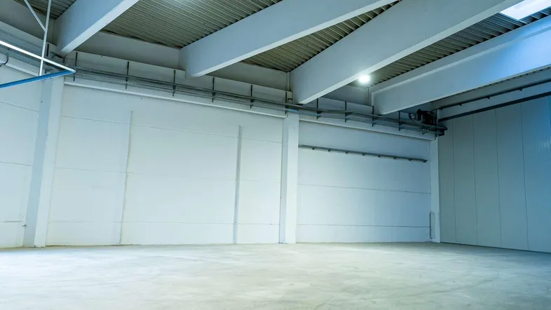 Geräumige, leere Lagerhalle mit hohen Decken und Betonboden, bereit zur Nutzung in neuwertigem Zustand.