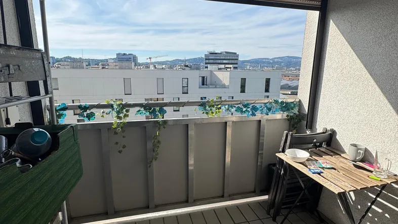 Heller Balkon mit Stadtblick, Fliesenboden und Jalousien für Privatsphäre.