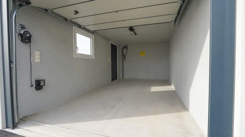 Helle und saubere Einzelgarage mit Fenster, Sektionaltor und Betonboden.